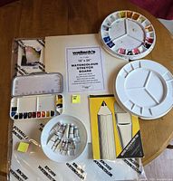 All items laid out: paper, stretch board, palettes, paint tubes, sketch pad