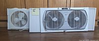 Two white window fans displayed together