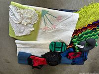 Wide shot showing the full assortment including folded blankets, crocheted doilies, soft bags, and a travel neck pillow.