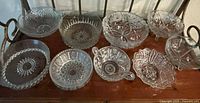 Photo of all ten assorted early 20th century crystal cut glass bowls arranged on a surface showing variety of patterns and shapes including footed and handled pieces.