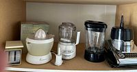 Photo showing a cream Toastmaster electric citrus juicer, white base Cuisinart Mini Prep food processor with clear container and blade, and a stainless steel Cuisinart blender with glass pitcher and black lid.