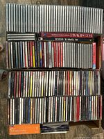 Two boxes filled with approx. 150 CDs in jewel cases showing a variety of music genres.