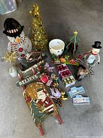 Various Christmas decorations including snowman figurines, decorative trees, wooden sled, lights, ornaments and candles.