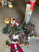 Overview of all Christmas decoration items including ceramic train, wreaths, stockings, candles, stuffed dog, small village houses, and storage bin.