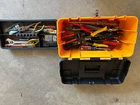 Open black and yellow Craftsman plastic toolbox showing assorted hand tools inside and removable tray with more tools and hardware.
