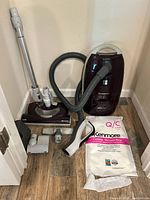 Full view of Kenmore Progressive canister vacuum and included accessories: wand, hose, floor brush, upholstery tool, small nozzle, vacuum bags.
