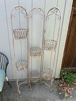 Full view of the metal plant rack with all three panels shown, displaying six round lattice metal holders for pots.