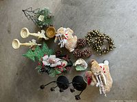 Photo showing a collection of Christmas-themed holiday decor items including reindeer figures, pine cones, candle holders, wreath, and decorative trees.