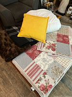 View of all bedding items including pillow, comforter, plaid blanket, faux fur throw, quilt, and shams arranged on furniture.