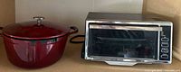 Red Kirkland Dutch oven and DeLonghi toaster oven side by side on countertop