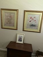 Overall view showing the set of two larger framed floral prints hung on wall and one smaller print on table below