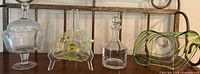 Lot of vintage glassware including candy dish with lid, swirl art glass bowl with green stripes, decanter, and cruet on metal stand