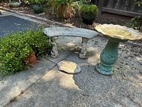 Wide view of bench, bird bath and memorial stone on a concrete patio