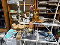Wide view of lot items on wire shelves and table showing plush toys, hanging decor, and trinkets
