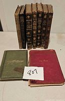 9 antique books displayed upright and lying flat, showing covers and spines; various conditions and colors including dark brown, green, red.