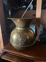 Front view of an antique brass spittoon showing 5 cent cigars emblem and overall shape.