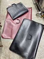 Three art portfolio bags placed on floor; largest burgundy bag shows a broken detachable handle inside, two smaller black bags placed on top