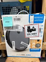 Front view of iHome AutoVac Juno robot vacuum in box with HomeMap navigation and warning label.