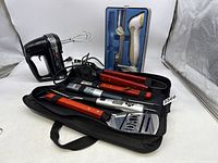 Photo showing Cuisinart hand mixer with beaters, Black & Decker electric knife in case, and DAD grill utensil set folded in case with two digital thermometers