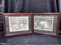 Two framed Lionel Barrymore sketch prints shown side by side, depicting detailed black and white rustic scenes with trees and buildings, in wooden frames
