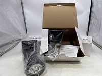 Opened box containing plastic-wrapped Magic Pro solar spotlight and instructions.