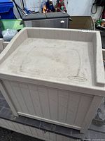 Overall view of the beige plastic mini deck box seat showing the top lid and sides.