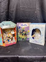 Full lot showing two Muffy bears in their original boxes and the collector's book in the center.