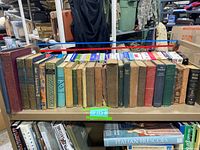 Books on a shelf, showing an assortment of old, hardcover books of varying sizes and colors, from close to full shelf length.