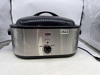 Front view of Oster roaster oven with lid and control knob showing the 22 quart capacity, stainless steel body, and power cord