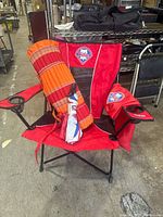 Full view of the red Philadelphia Phillies folding chair with umbrella sleeve and striped yoga mat.