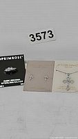 Three pieces of Primrose sterling silver jewelry displayed with tags: a ring and two pairs of earrings.