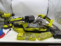 Wide view of circular saw, two drills, batteries, chargers, bag, bit cases and accessories