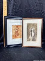 Two framed art prints placed side by side on black fabric background with a ruler indicating size.