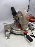 Front and side view of red and silver SkilSaw 3316 miter chop saw showing blade guard, handle, and base with angle gauge.