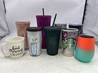 Front view showing all ten tumblers and mugs, a mix of Starbucks, Tervis, and other brands in various colors and textures