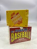 Stacked view of unopened 1990 Score Rookie & Traded Card Set on top of 1991 Fleer Baseball Update trading cards box, both sealed in shrink wrap.