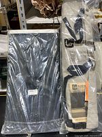Two sealed items in plastic packaging: The Stair Barrier fabric gate and a Night N Dawn black laundry hamper.
