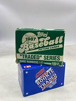 Two stacked boxes; top is green and white 1987 Topps Baseball "Traded" Series box, bottom is blue 1989 Score Rookie & Traded card box