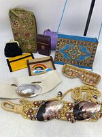 Photo of entire lot showing various wallets, change purses, two shell belts and a fabric zippered bag with floral pattern