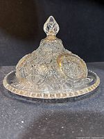 Side view of the domed butter dish showing the starburst pressed glass pattern, faceted knob top, and sawtooth edge on plate base.