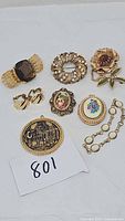 Full shot of vintage jewelry including pins, earrings, pendants, and commemorative piece