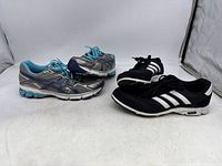 Photo of two pairs of women's sneakers: Adidas black size 10 and ASICS silver/blue size 9.5.