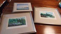 All three framed artworks on tabletop