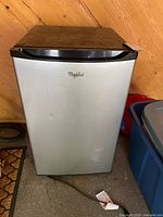 Front view of Whirlpool mini fridge showing stainless door and dent
