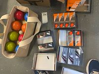 Bag containing bocce balls beside boxed golf balls