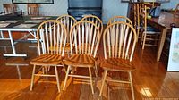 Front view of four of the six matching wood Windsor chairs