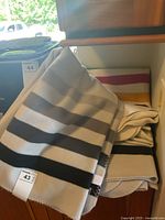 Folded grey stripe blankets over counter, multicolour stripe blanket beneath