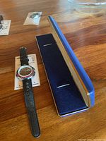 Watch beside open blue presentation box on wooden surface