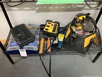 Shelf view with Dewalt sander in bag, drill bit cases, Stanley case, power bar, mallet