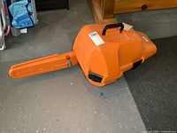 Closed orange Stihl hard case with bar scabbard attached